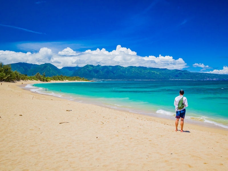 Man standing on sands of Baldwin Beach, located in Paia, Maui