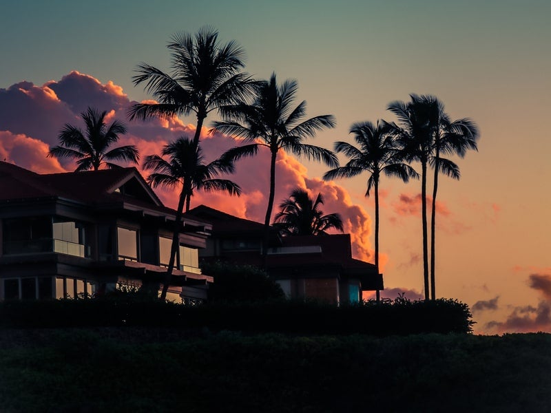 Silhouette of oceanfront villa and palm trees at sunset in Wailea, Maui